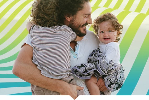 father smiling and holding his son and daughter